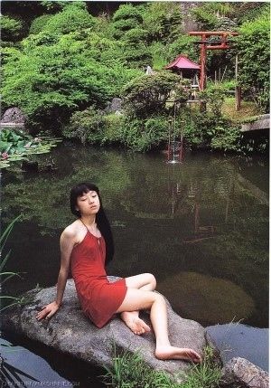 池の岩場で座る美女