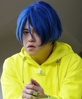 青い髪型に黄色いパーカー姿の渋谷慶一郎さん