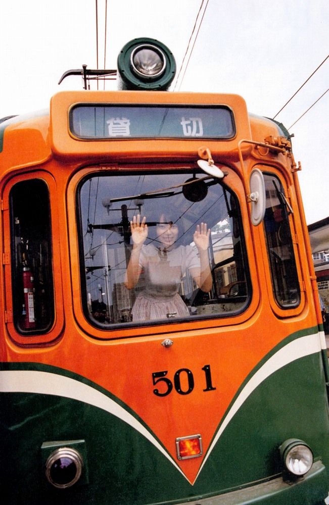 オレンジの路電電車の窓から微笑む宮脇咲良さん